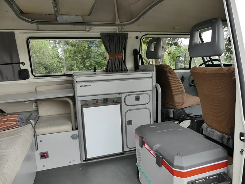 petite-img-tao-10 Image de l'équipement intérieur de "Tao" en bivouac en pleine nature en Rhône Alpes. On peut voir la plaque de cuisson, le frigo et l'évier Ce van est en location chez Ryôko - spécialiste de la location de vans pour slow travel dans la Loire.
