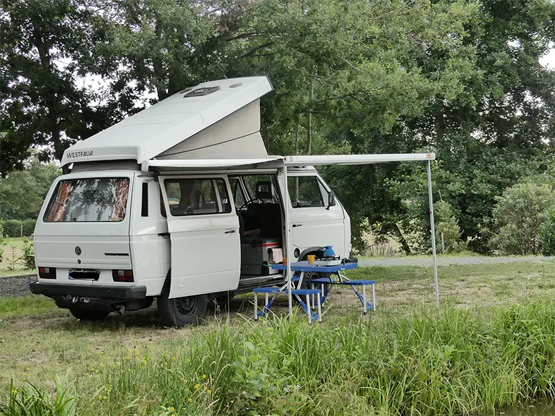 petite-img-tao-2 Image de "Tao" en bivouac en pleine nature en Rhône Alpes. La table et les chaises sont sorties ainsi que le store latérale. Ce van est en location chez Ryôko - spécialiste de la location de vans pour slow travel dans la Loire.