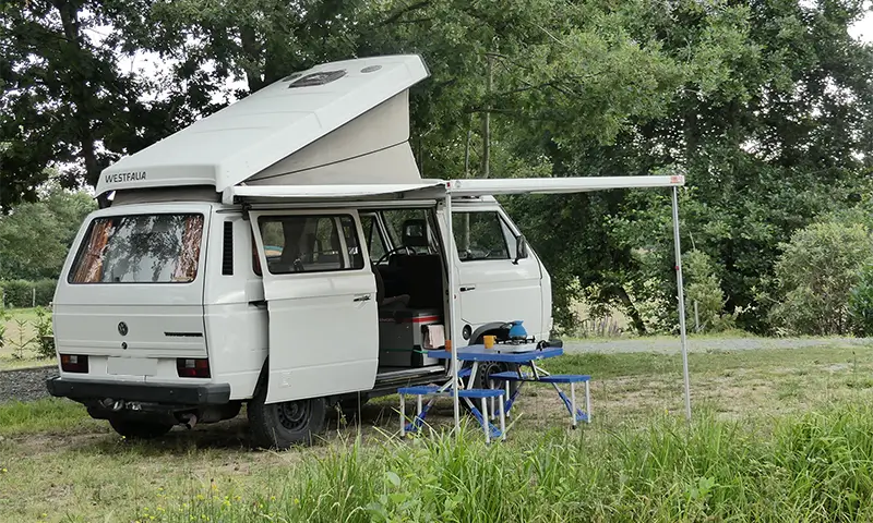 Image de "Tao" en bivouac en pleine nature en Rhône Alpes. La table et les chaises sont sorties. Ce van est en location chez Ryôko - spécialiste de la location de vans pour slow travel dans la Loire.